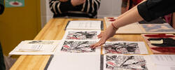 A RISD student displays their final project work on a wooden table.