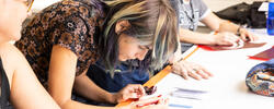 A person is leaning over a table focusing on a stencil project.