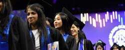 A group of RISD graduates are exiting Commencement with degrees in hand and smiling faces.