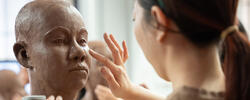 An artist at RISD is sculpting a head out of brown clay.