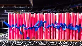 RISD diplomas with blue ribbons tied around them are on a stand, ready to be distributed at Commencement. 