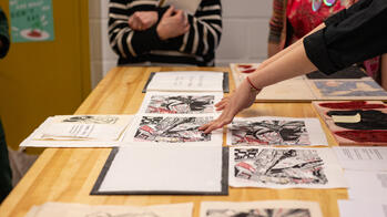 A RISD student displays their final project work on a wooden table.