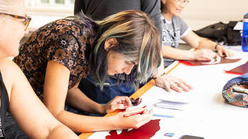A person is leaning over a table focusing on a stencil project.