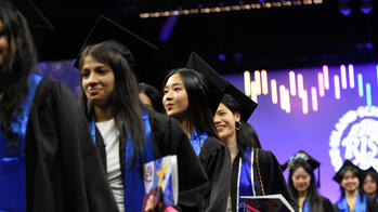 A group of RISD graduates are exiting Commencement with degrees in hand and smiling faces.