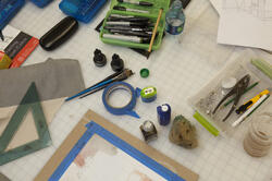 A top view of a busy RISD workdesk with various art supplies. 