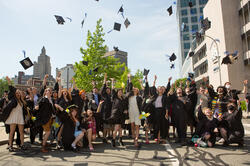A large group of graduated RISD students throw their caps in the air.