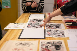 A RISD student displays their final project work on a wooden table.